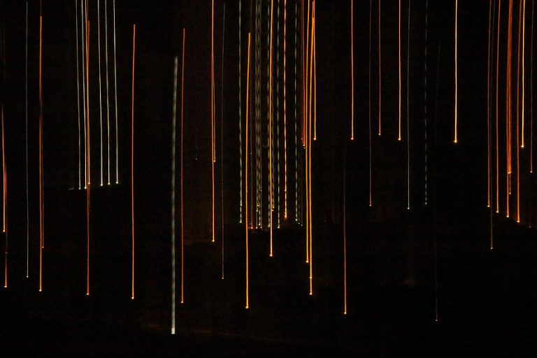 Vertical streaks of orange and white light on a dark background