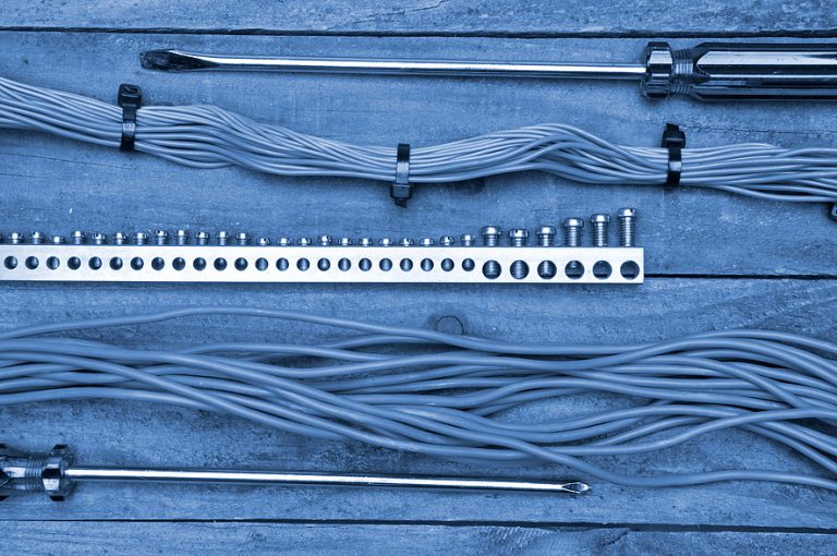 Electrical wires, screwdrivers, and terminal strip laid out on a wooden surface
