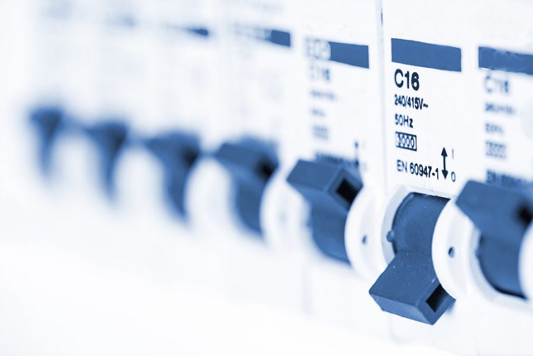 Close-up of electrical circuit breakers with blue switches